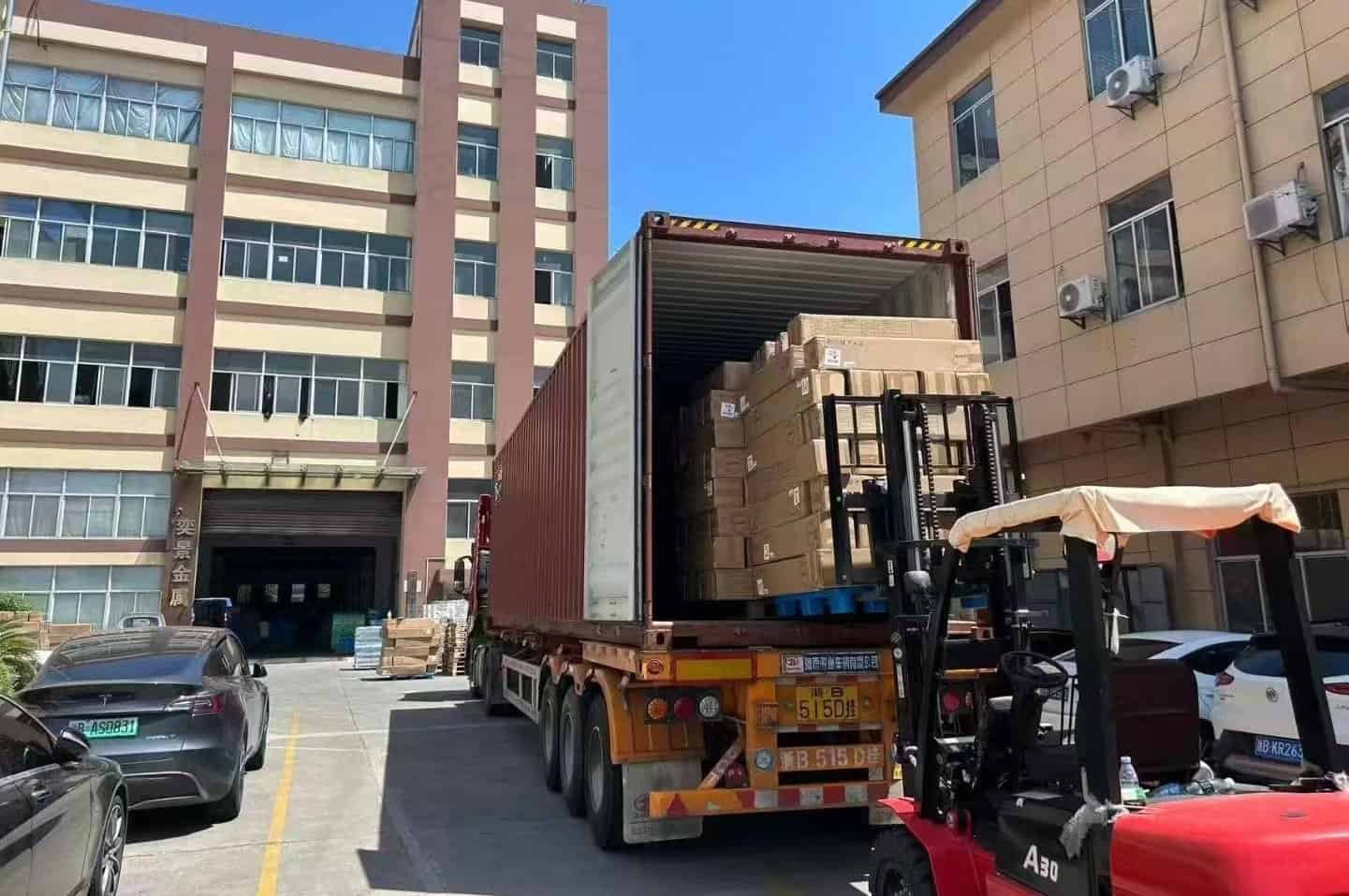Heavy-duty forklift unloading cardboard boxes from a shipping container at a commercial storage facility.