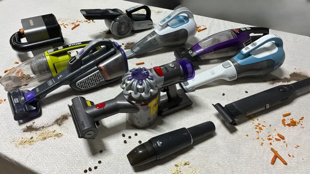Vacuum cleaner with multiple attachments on a table.