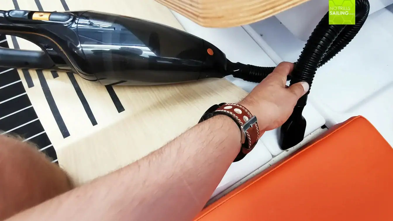 Hand holding vacuum cleaner hose on car dashboard for cleaning.