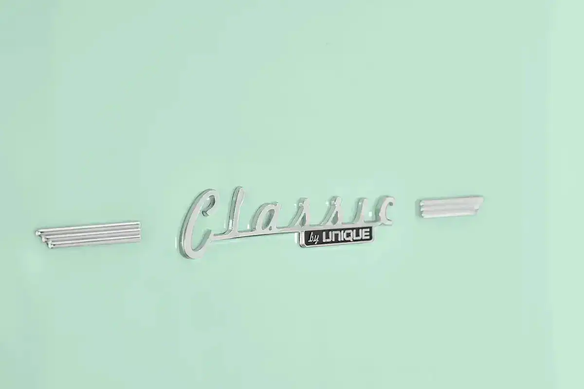 Emblema de carro clássico com o texto 'Classic by Unique' em um fundo verde-menta.