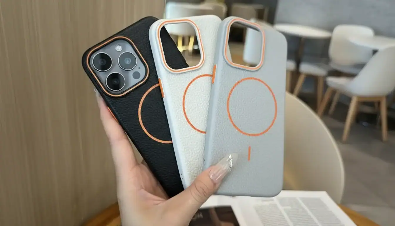 Person holding three smartphone cases with camera cutouts, featuring black, white, and gray colors with a minimalist design.