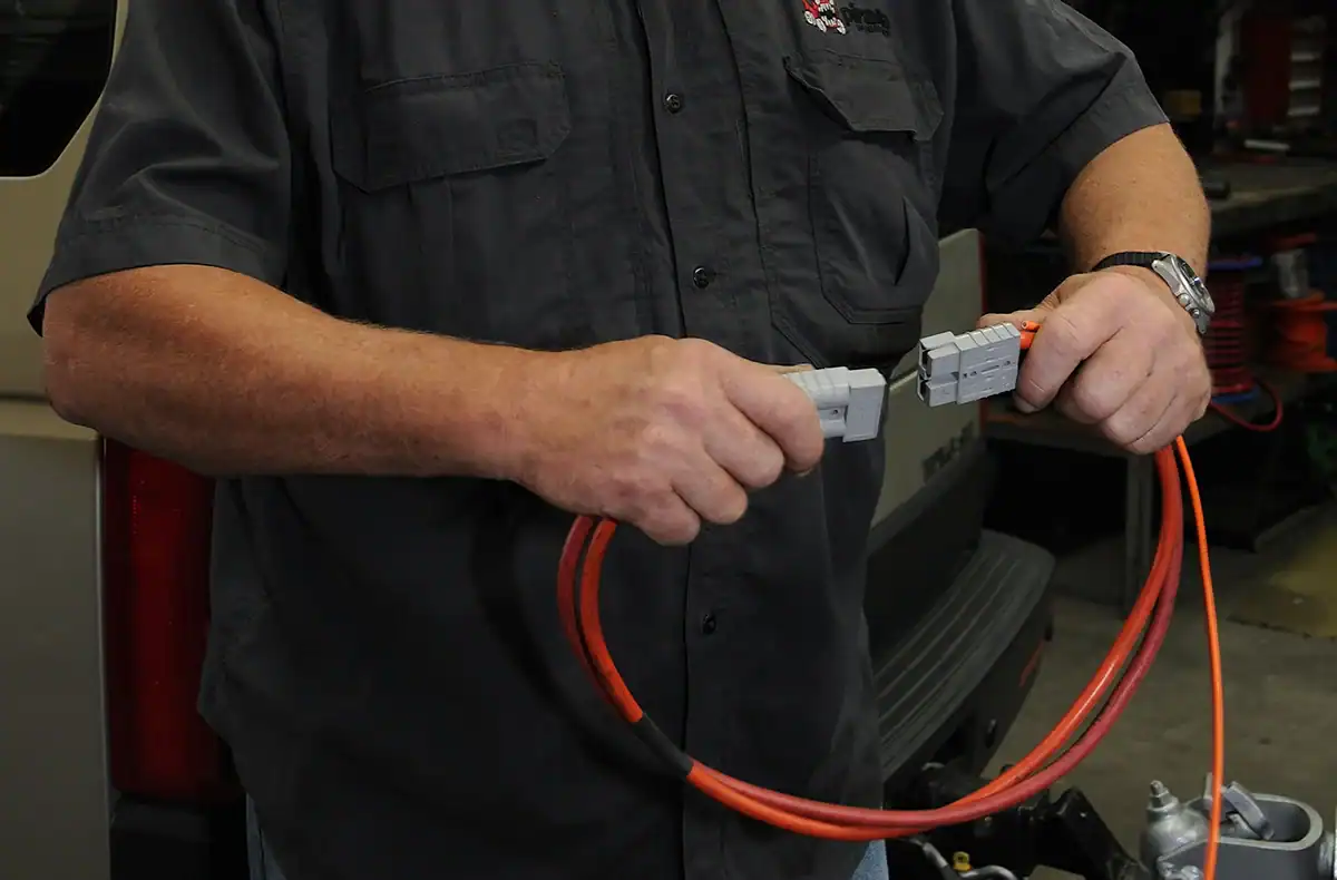 작업장 환경에서 두 개의 전기 케이블을 연결하는 검은색 셔츠를 입은 남성.