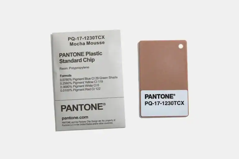 Pantone plastic standard chip labeled PQ-17-1230TCX Mocha Mousse with accompanying information card.