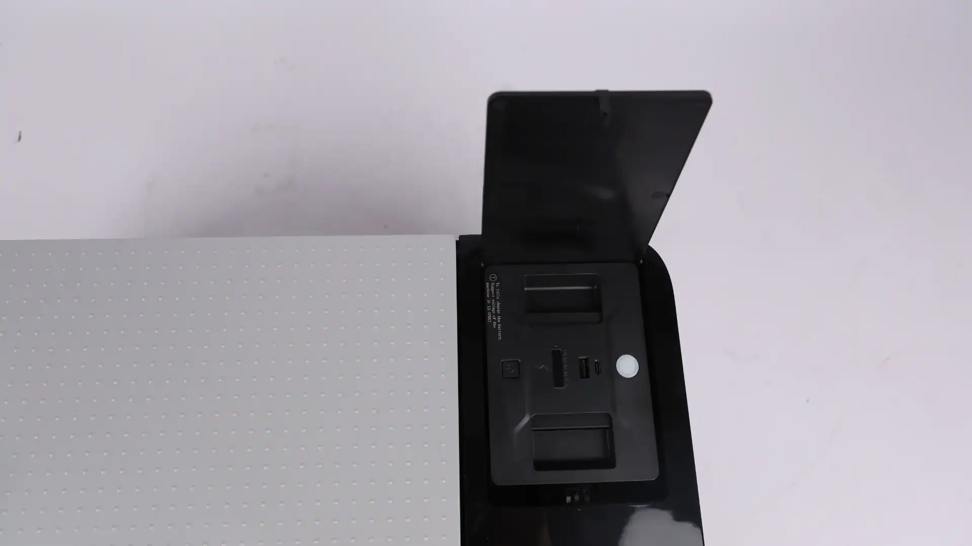 A portable car fridge featuring a USB charging slot and internal compartments, with a black hinged lid partially open.