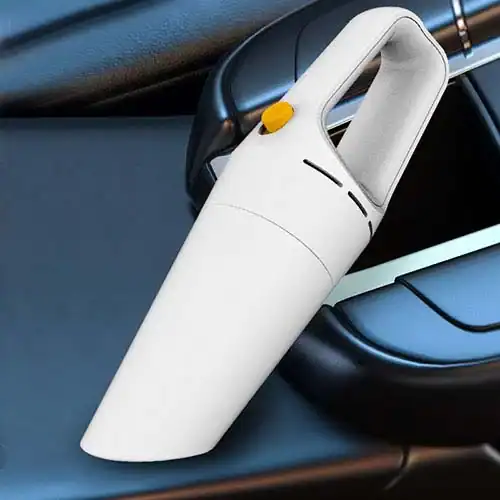 Handheld, white portable vacuum cleaner placed on a car seat, designed for easy car interior cleaning with an ergonomic handle.