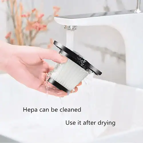 A hand washing a cylindrical HEPA filter under running water in a sink, with text stating 'Hepa can be cleaned. Use it after drying'.