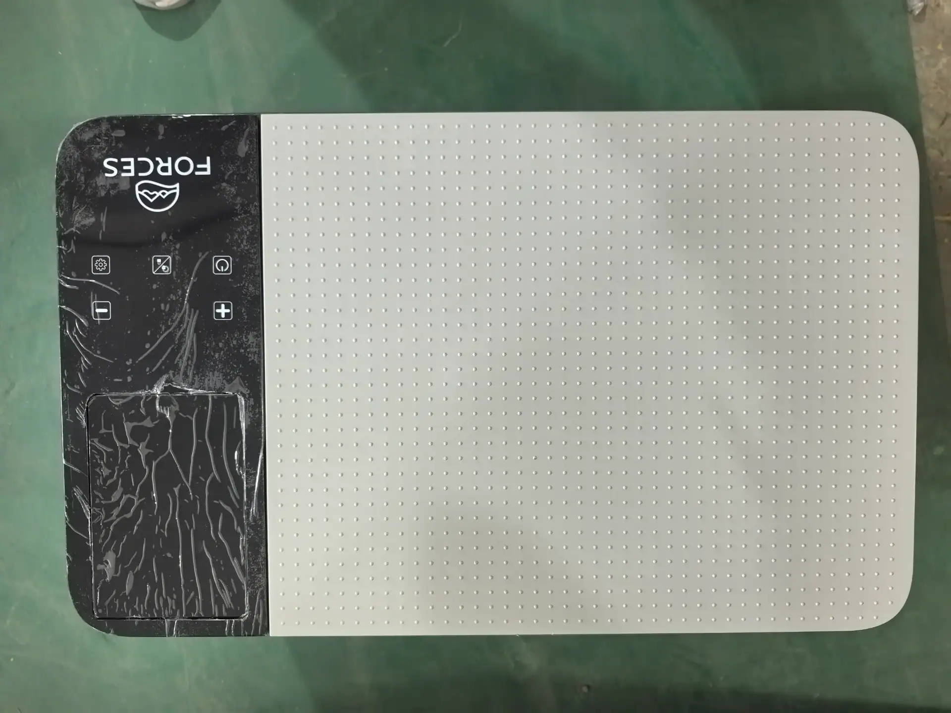 A white panel with a dotted grid pattern on the right and black digital control panel featuring buttons and icons on the left.
